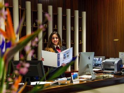 Eine Frau steht hinter einem Empfangstresen in einem modern eingerichteten Büro mit Holzvertäfelung.