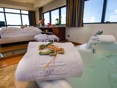 Luxuriöses Hotelzimmer mit großem Bett, Whirlpool und Handtuch mit Badesalz und Stäbchen.