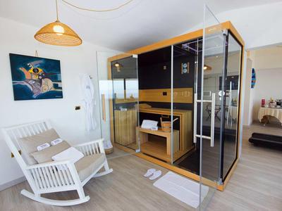 Moderner Raum mit Holz-Sauna, weißem Schaukelstuhl, Teppich und Kunstbild an der Wand.