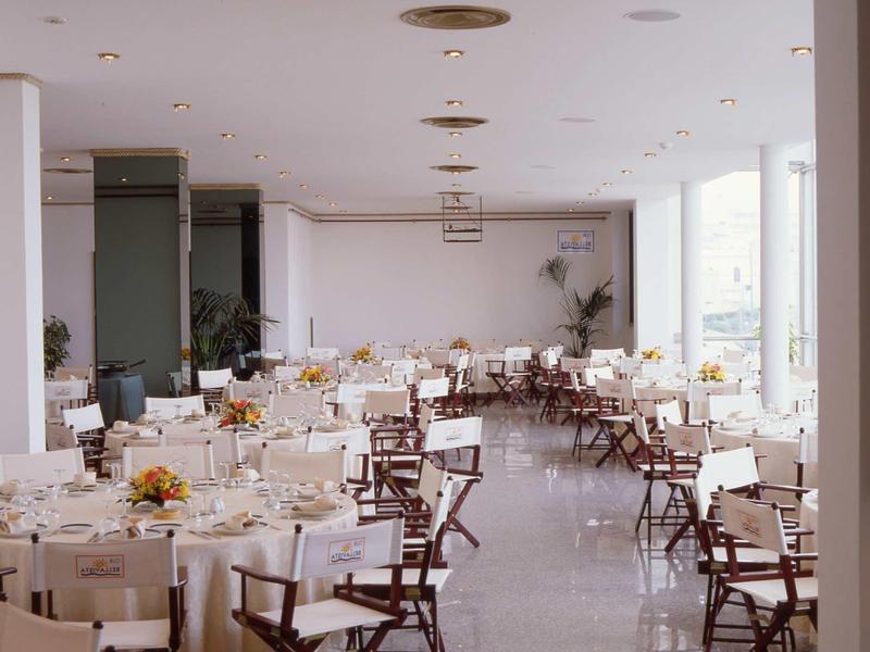 Großer heller Festsaal mit vielen gedeckten Tischen und Stühlen, heller Boden, große Fenster.