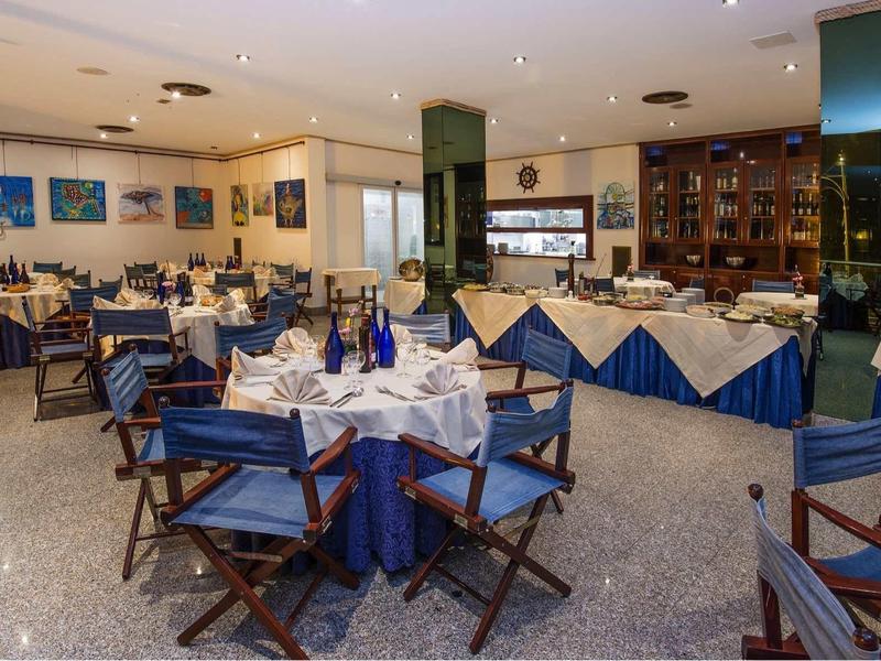 Restaurant mit blauen Tischdecken, gefalteten Servietten und dunkelbraunen Holzstühlen.