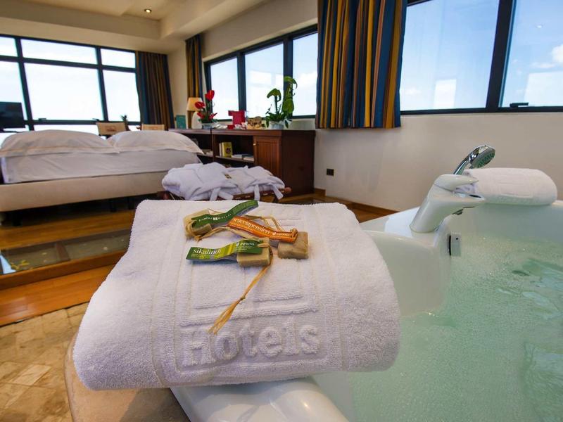 Luxuriöses Hotelzimmer mit großem Bett, Whirlpool und Handtuch mit Badesalz und Stäbchen.