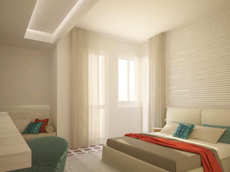 Hell eingerichtetes Schlafzimmer mit großem Fenster, Doppelbett, grünem Sessel und weißer Wandverkleidung.