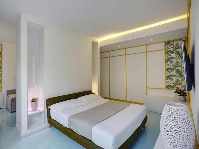 Modernes Schlafzimmer mit großem Bett, weißen Wänden, eingebautem Schrank und minimaler Dekoration.