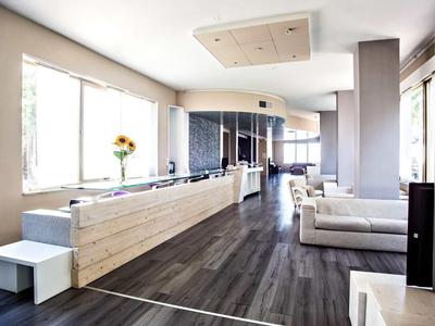 Heller, moderner Raum mit großen Fenstern, dunklem Holzboden und hellem Sitzbereich.