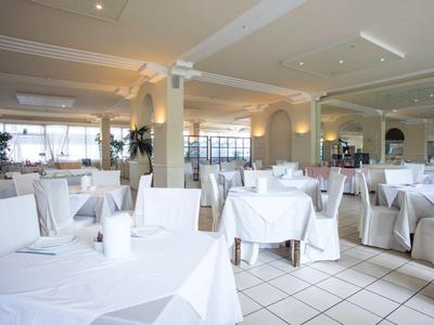 Restaurant lumineux et moderne avec des tables et chaises couvertes de blanc.