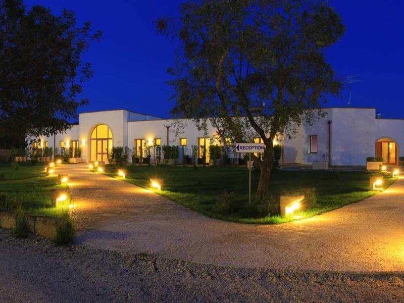 Beleuchtetes modernes Gebäude mit Treppen, umgeben von Bäumen und Wegen bei Nacht.