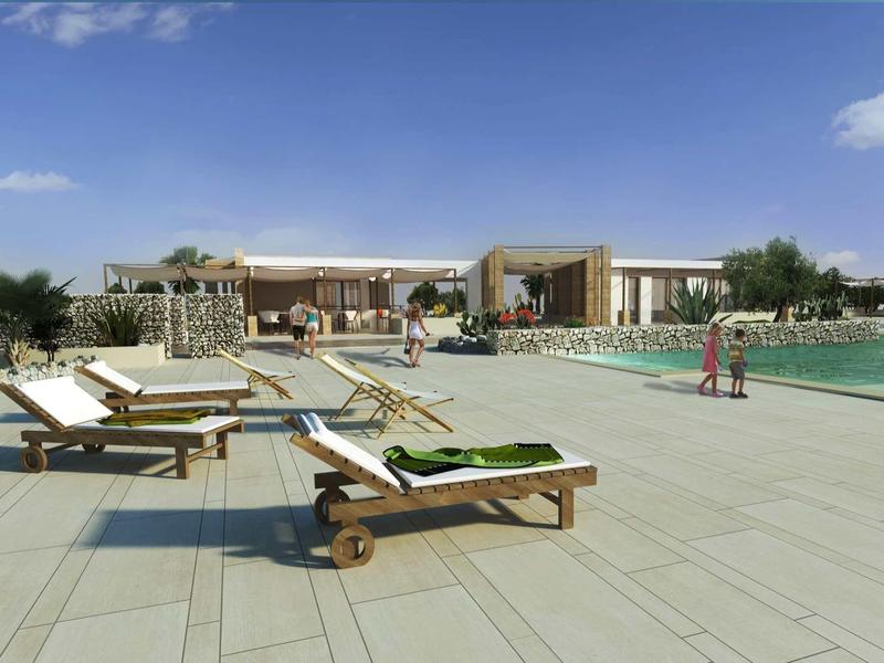 Modern hotel pool area with lounge chairs and clear sky.