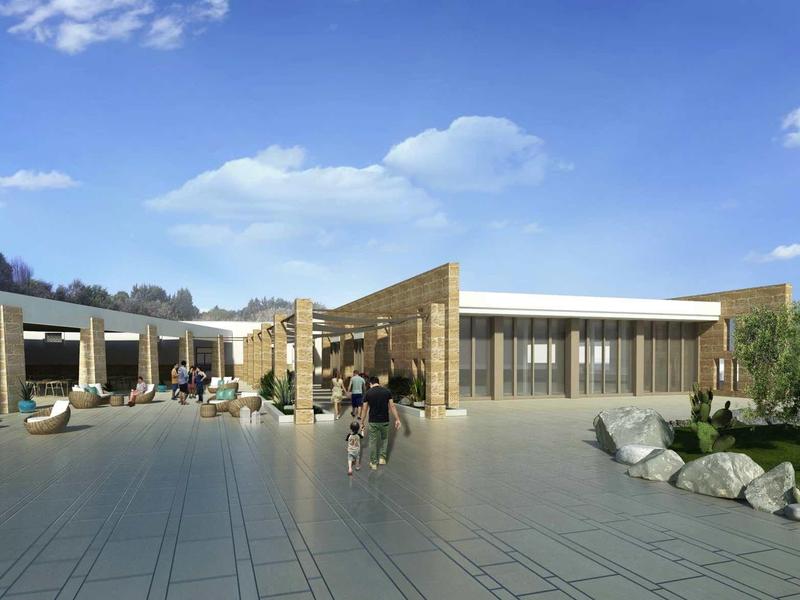 Modern hotel complex with spacious paved courtyard and seating areas under a blue sky.