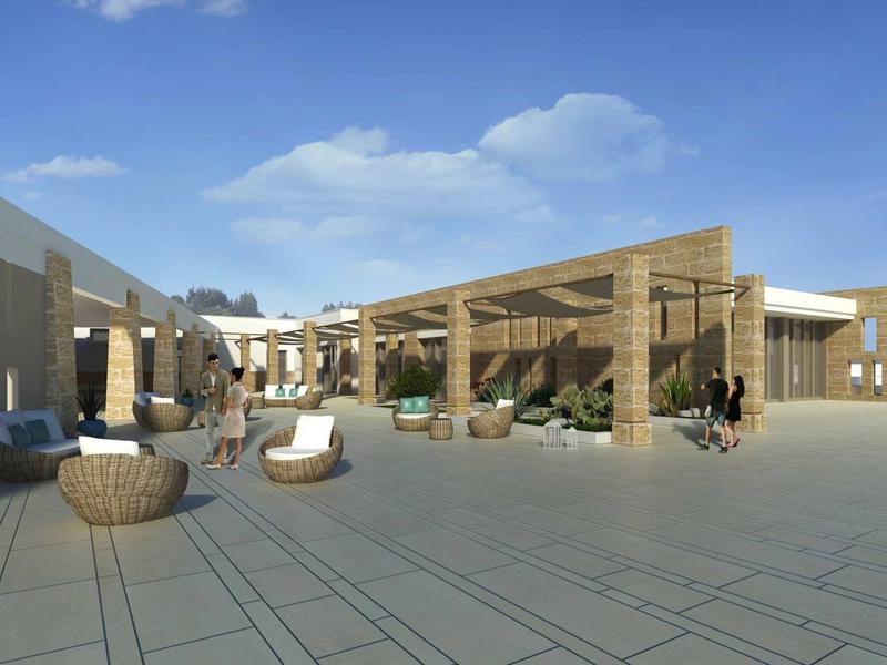 Modern hotel courtyard with wooden structure and seating areas under clear sky.