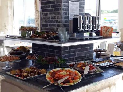 Buffet con varios platos y máquinas de café en un comedor luminoso