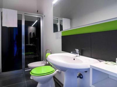 Modern bathroom with white sink and green toilet seats.