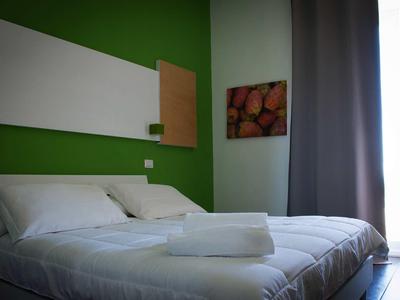 Clean, modern hotel room with two single beds, white bedding, and green wall.
