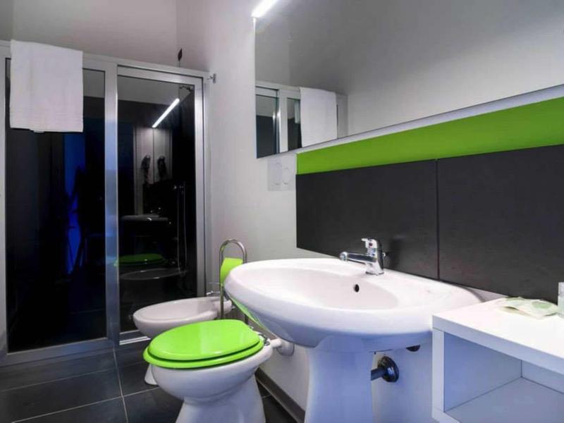 Modern bathroom with white sink and green toilet seats.