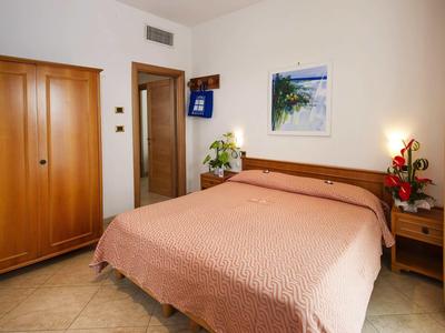 Gemütliches Schlafzimmer mit Doppelbett, Holzmöbeln und heller Wanddekoration.