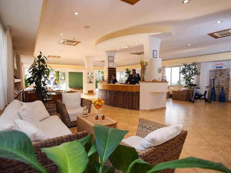 Großer, heller Wohnraum mit Korbmöbeln, Pflanzen und Theke in warmem, gemütlichem Ambiente.