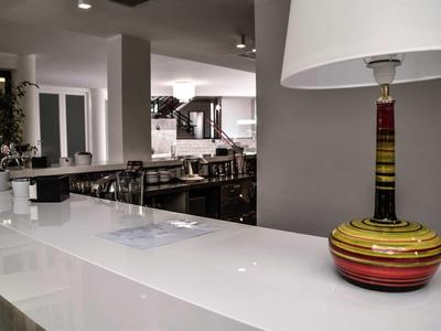 Área de restaurante de hotel moderna con mostrador blanco largo y lámpara de mesa colorida en primer plano.