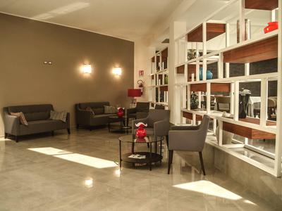 Área moderna del vestíbulo del hotel con sofás, sillones y estantes en la pared.