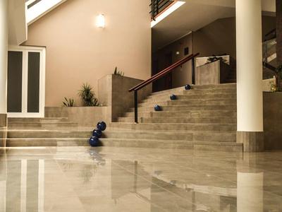 Área interior moderna con escaleras, sillón tapizado y suelo de mármol reflectante