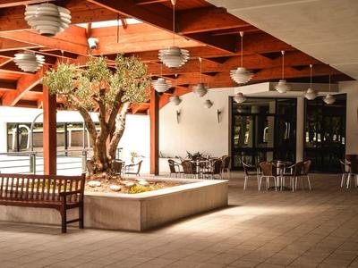 Überdachter Innenhof mit Holzbalkendecke, Sitzbänken und großem Baum in einem quadratischen Pflanzbeet.