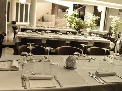 Eleganter, gedeckter Esstisch mit weißen Tüchern, Gläsern und Besteck in stilvollem Raum.