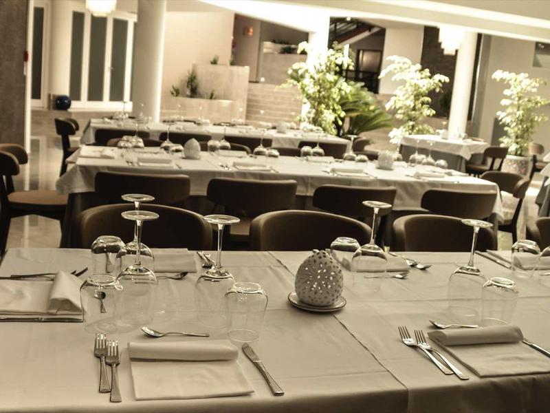 Eleganter, gedeckter Esstisch mit weißen Tüchern, Gläsern und Besteck in stilvollem Raum.