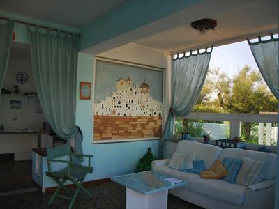 Pohodlná posezení s pohovkou a židlí na zastřešené terase s výhledem na moře.