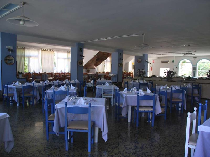 Großer, leerer Speisesaal mit blau gestrichenen Holzmöbeln und weiß blauen Tischdecken.