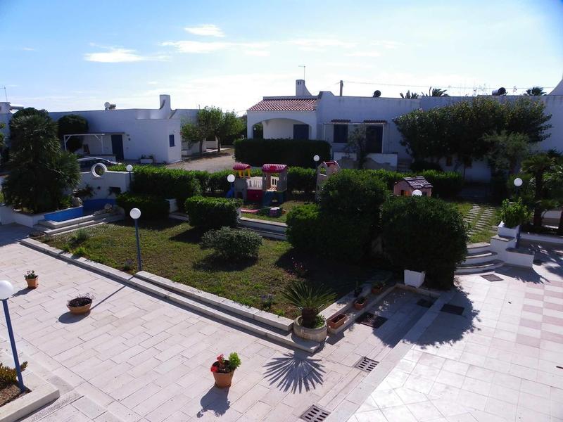 Ein gepflegter Garten mit bepflanzten Beeten und weißen Einfamilienhäusern im Hintergrund.