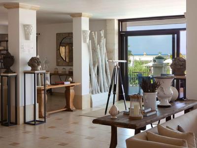 Helles Wohnzimmer mit großen Fenstern, Holztisch, modernen Statuen und Blick ins Freie.