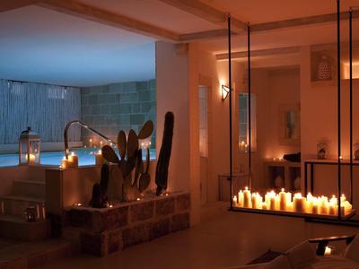 Gemütlicher Raum mit Kerzen, halbrundem Pool, Sitzgelegenheiten und warmem Licht.