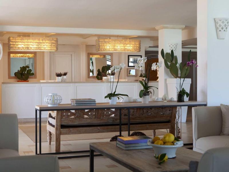 Helles Wohnzimmer mit Sofa, Holztisch, Spiegelwand und Pflanzen in modernen weißen Wänden.