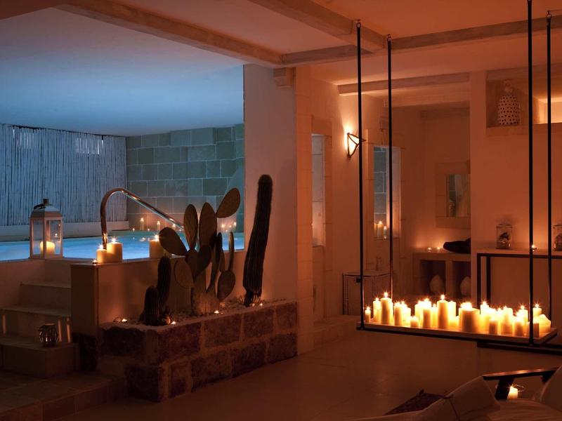 Gemütlicher Raum mit Kerzen, halbrundem Pool, Sitzgelegenheiten und warmem Licht.