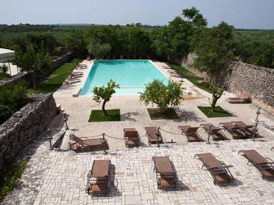 Rechteckiger Pool mit Liegestühlen auf gepflastertem Hof, umgeben von Natur und Steinmauern.