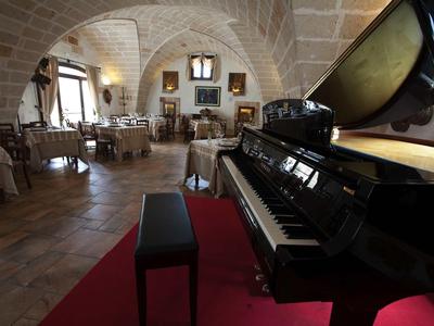 Un comedor elegante con un piano de cola negro y alfombra roja en un entorno histórico.