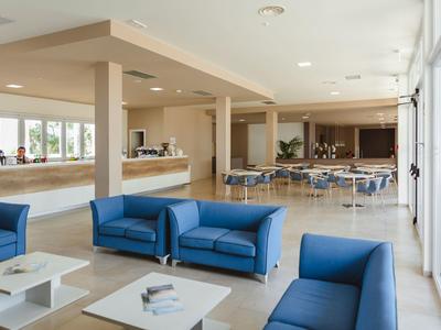 Helles, modernes Wohnzimmer mit blauen Sofas, weißen Tischen und großem Fensterfront auf der rechten Seite.