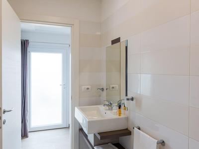 Moderner, heller Badezimmerrraum mit Waschbecken, Bidet, Handtuchhalter und großem Spiegel.