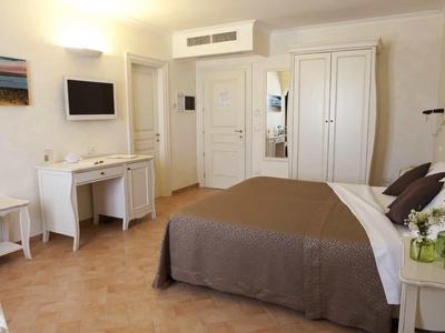 Hell eingerichtetes Schlafzimmer mit großem Bett, kleinem Schreibtisch und weißem Schrank.