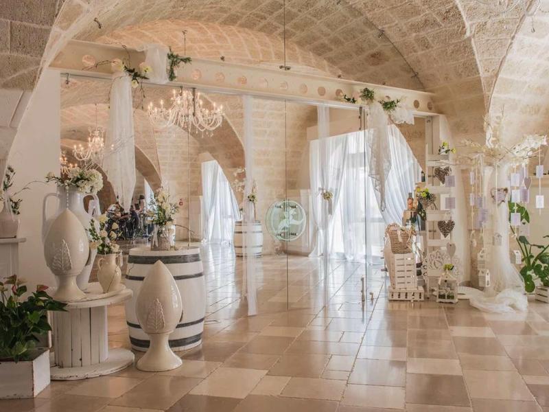 Heller, eleganter Saal mit gewölbten Decken, Marmorboden, dekorativen Säulen und Pflanzen.