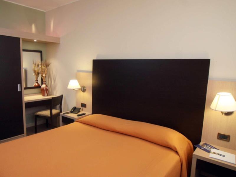 Ein Schlafzimmer mit großem schwarzen Kopfteil, orangefarbenem Bett und zwei Nachttischlampen.