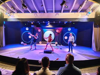 Zwei Tänzer führen auf einer Bühne mit buntem Licht vor Publikum auf.