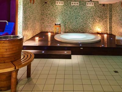 Eleganter Wellnessraum mit Mosaikfliesen, Rundwanne, Holzbottichen und warmem Licht.