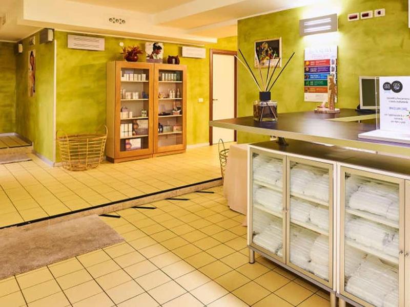 Heller Hotel-Empfang mit grünen Wänden, Holzrezeption und Regal mit Glastüren.