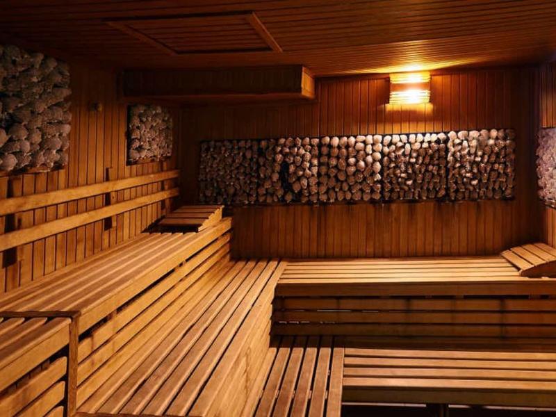 Innenraum einer Sauna mit mehrstufigen Holzliegen und warmem Licht an der Decke.