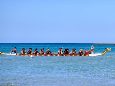 Smocza łódź z wieloma wioślarzami na spokojnym morzu pod czystym niebem.