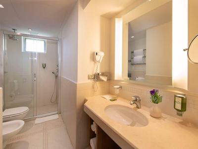 Helles, modernes Badezimmer mit Waschbecken, Spiegel und begehbarer Dusche.