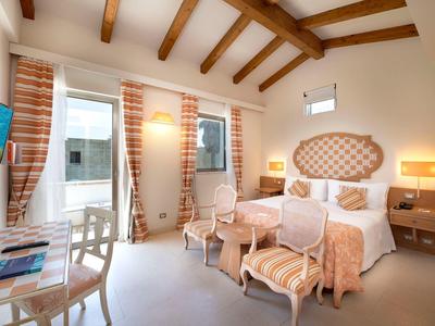 Helles Hotelzimmer mit Doppelbett, Holzbalkendecke und Zugang zum Balkon.