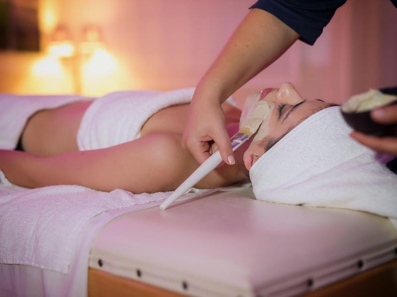 Frau genießt Gesichtsbehandlung in einem entspannenden Spa-Umfeld.