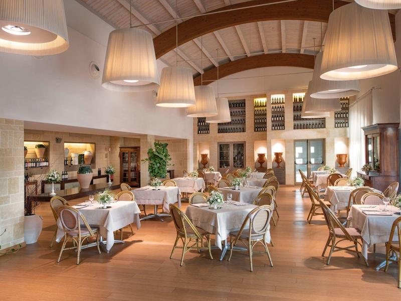 Helles, freundliches Restaurant mit runden Tischen, Korbstühlen und großen Lampenschirmen.