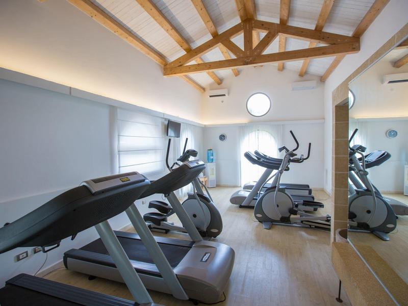 Moderner Fitnessraum mit Laufbändern und Crosstrainern in hellem Raum mit Holzbalken.